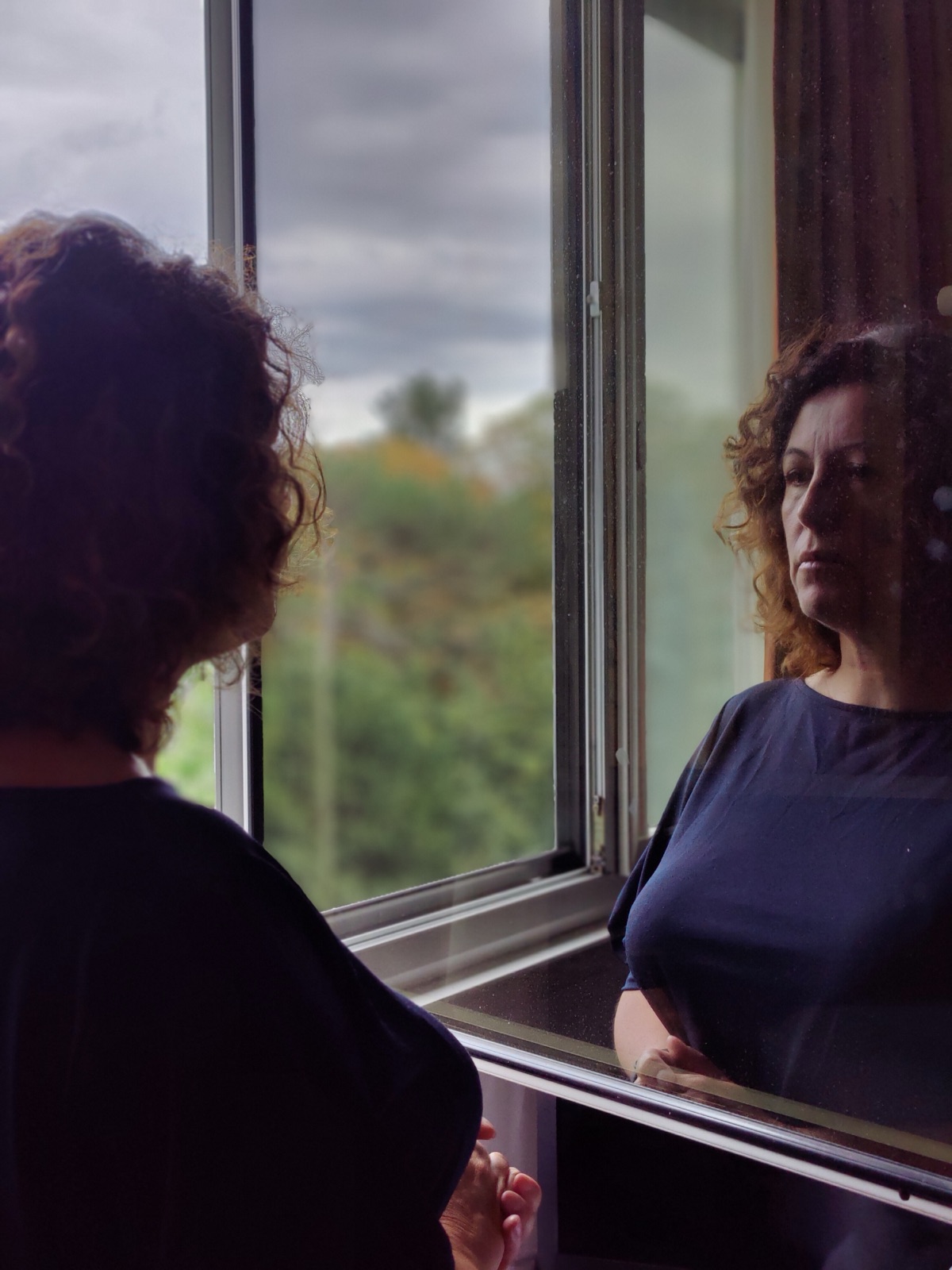 Une femme à sa fenêtre, et son reflet dans la vitre